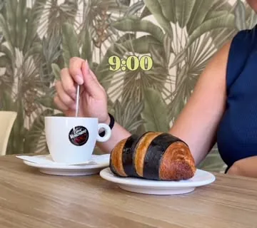 Caffè e croissant bicolore sul tavolo, alle 9 del mattino